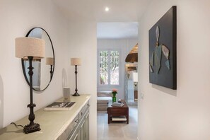 A hallway with a mirror, two lamps, a stack of books, a coffee table with a vase, and a painting on the wall. - Home Art - Central, fantastic garden and quiet (Nice)
