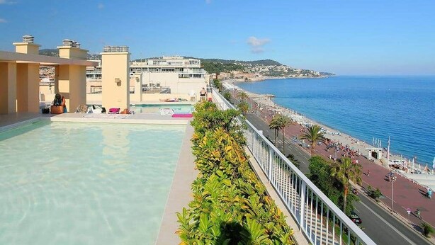 Una piscina en la azotea con vistas al mar y al paisaje urbano.