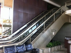 Eine Rolltreppe im Inneren, mit einem Schild, das den Zugang zum 'Bureau de l'Escalier' und zur 'Salle' anzeigt.