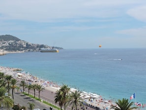 Eine Küstenstadtlandschaft mit Strand, Palmen und einem Schiff in der Ferne.
