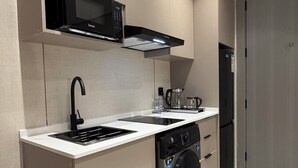 Una cocina compacta equipada con microondas, cafetera y lavadora.