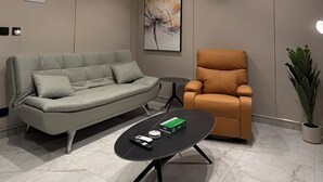 Una sala moderna con sofá, sillón, mesa de centro y un cuadro en la pared.