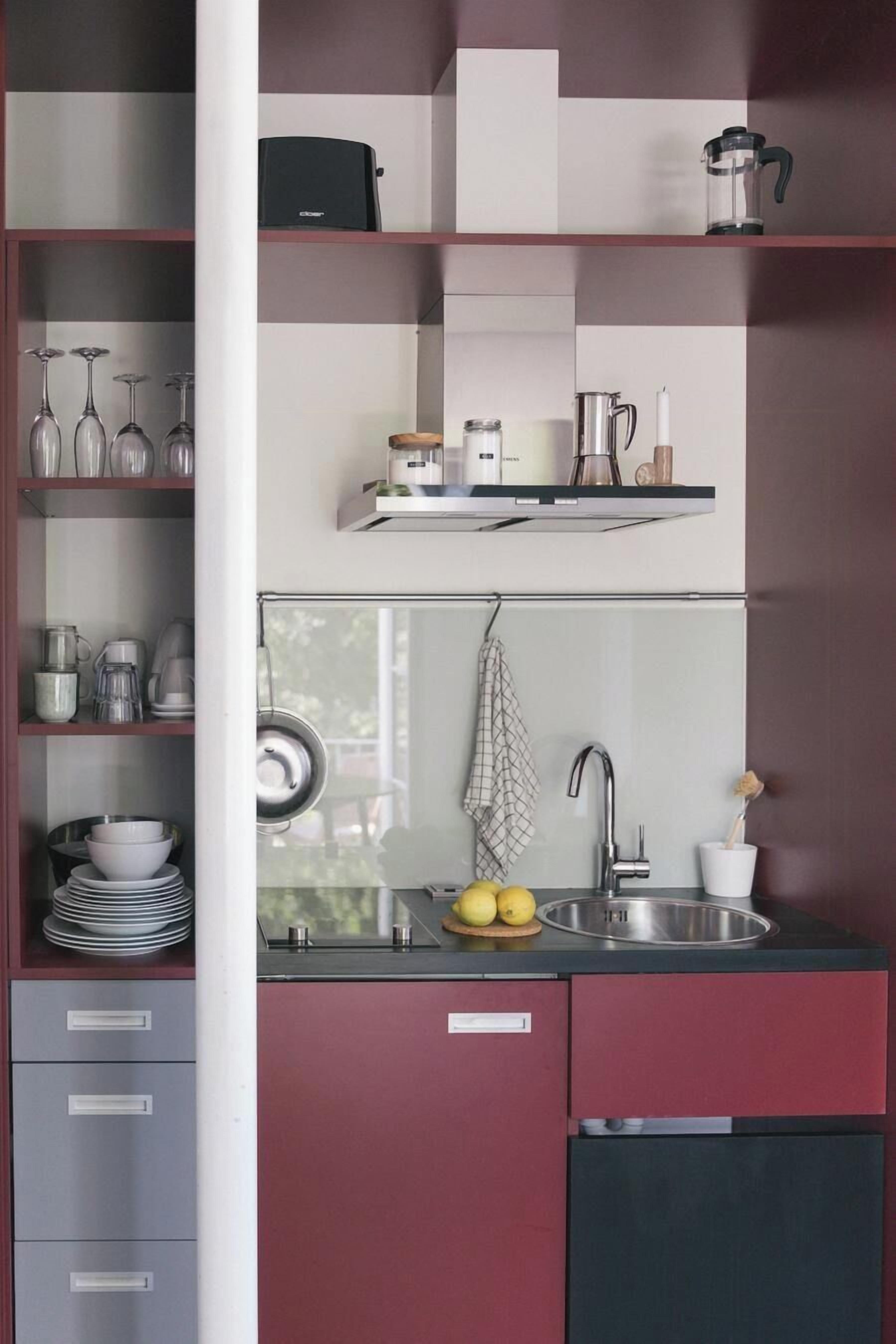 Eine moderne Küche mit integriertem Spülbecken, einer Kaffeemaschine und einem Regal mit Gläsern.