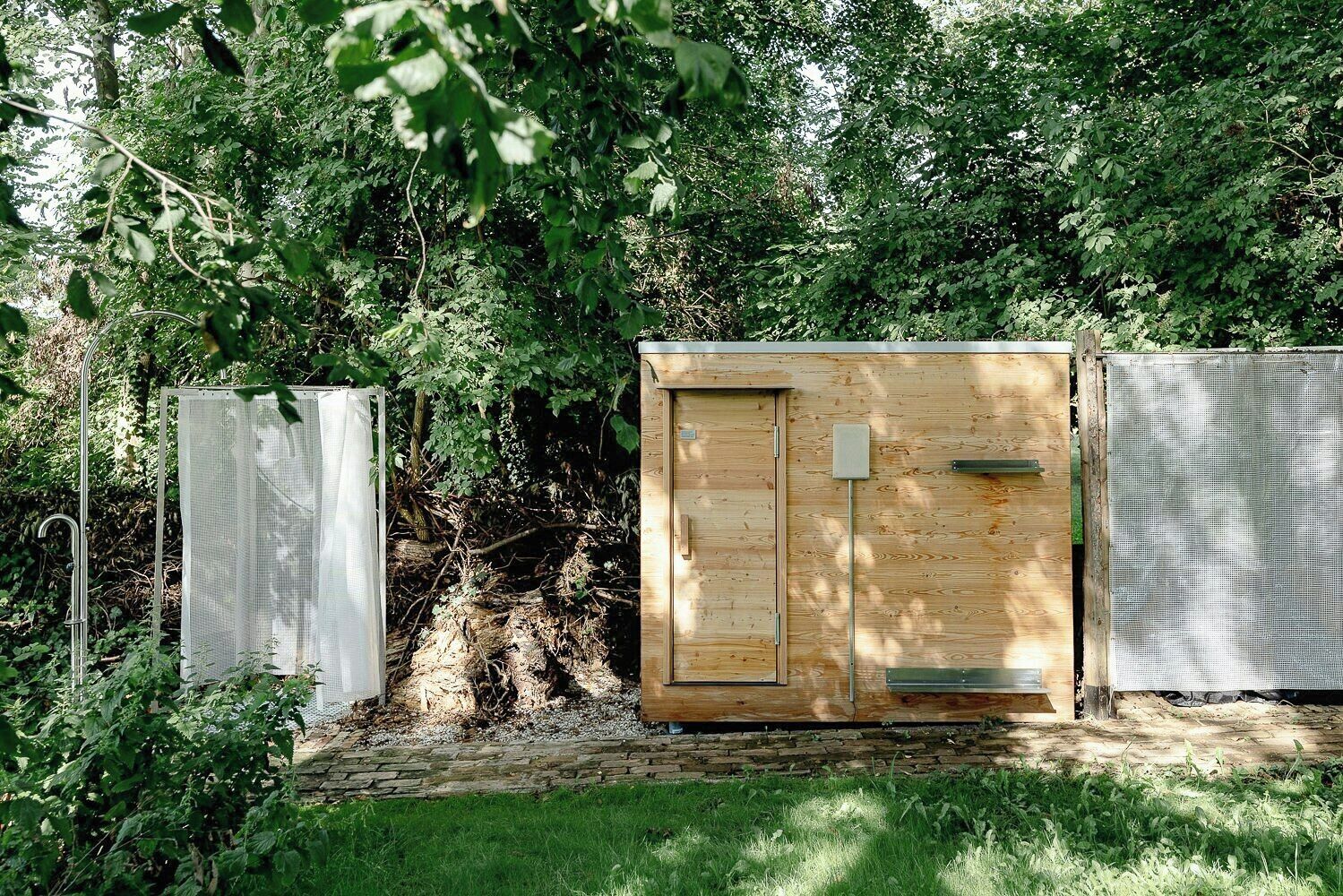 Una construcció de fusta amb una porta, una malla metàl·lica i un pal metàl·lic.