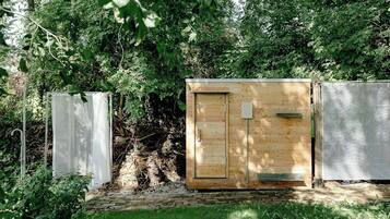 Una construcció de fusta amb una porta, una malla metàl·lica i un pal metàl·lic.