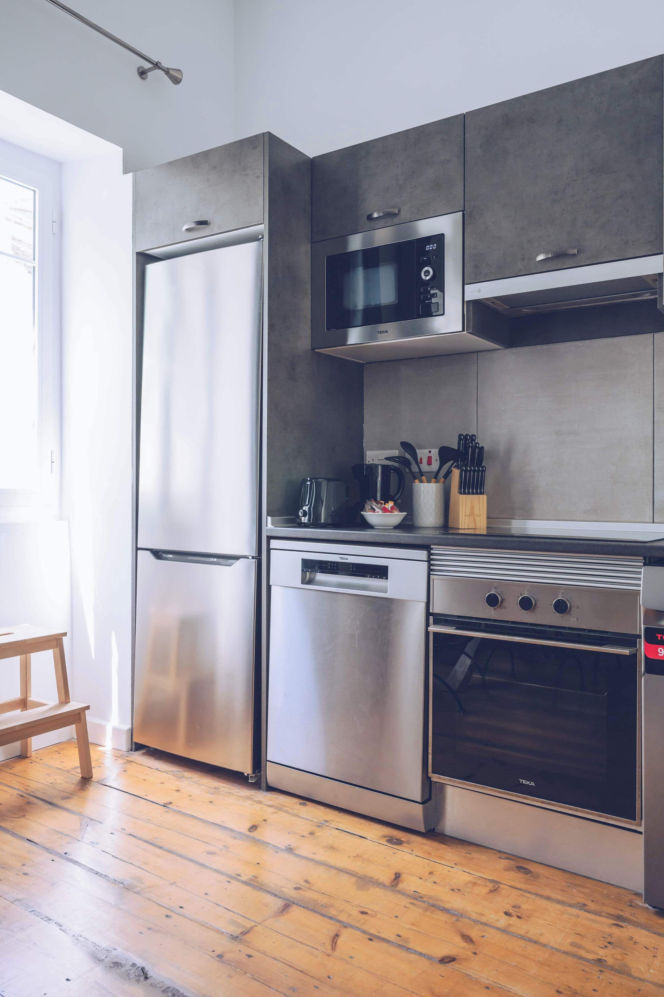 A modern kitchen with stainless steel appliances, a microwave, and a wooden floor.