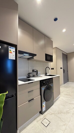 Una cocina moderna equipada con lavadora integrada, microondas y cafetera.