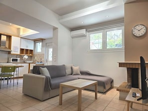 Una sala de estar moderna con un sofá, una mesa de centro, una chimenea y una zona de cocina con microondas y armarios.