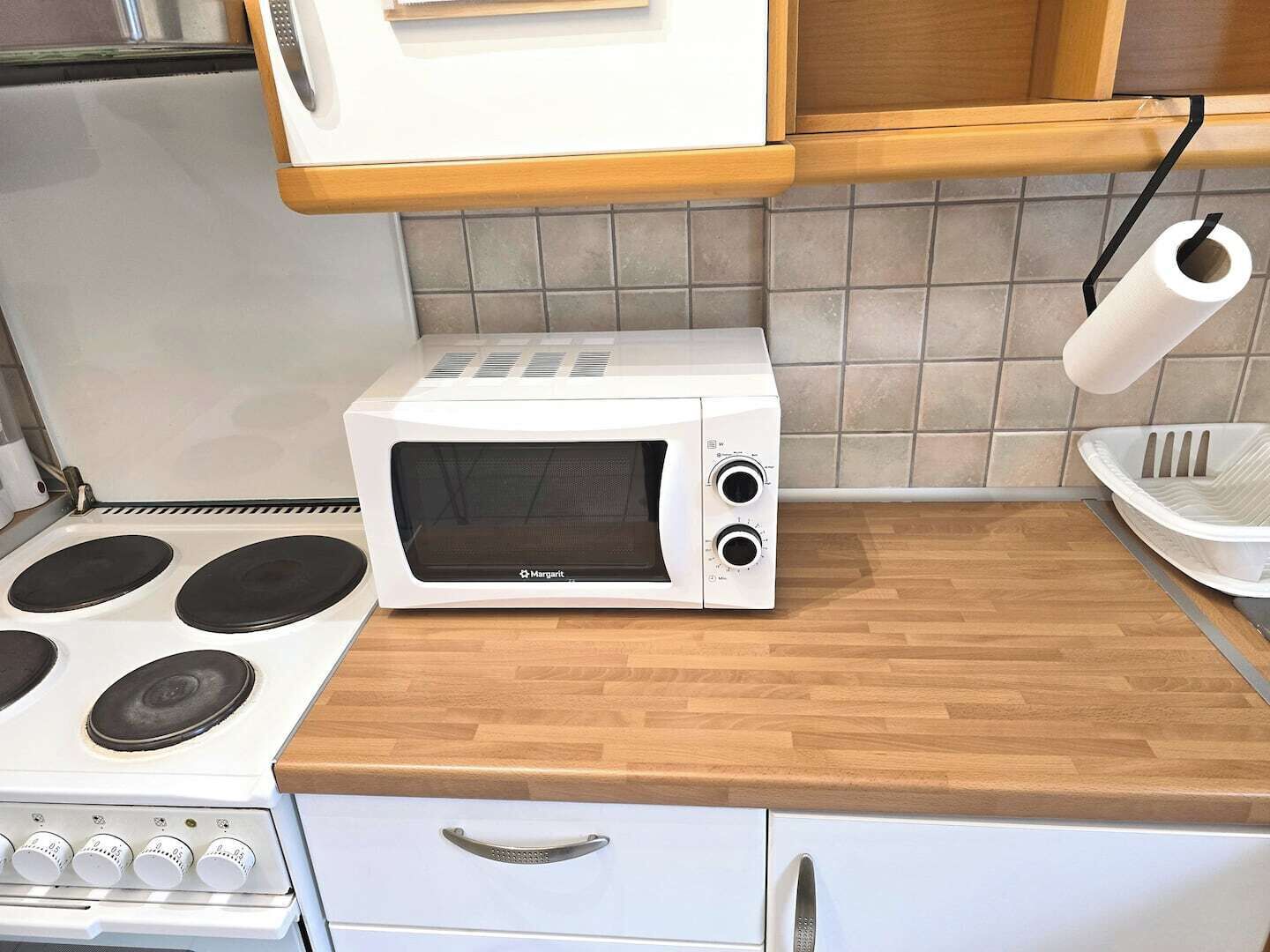 Una cocina con microondas blanco, estufa y encimera de madera.