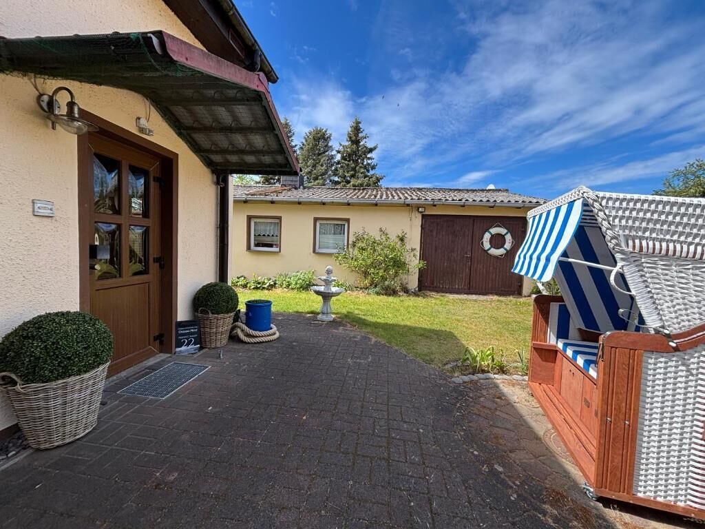 A building with a wooden door, a small garden, and a blue and white striped awning.