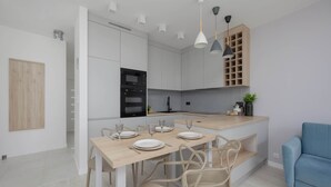 Eine moderne Küche mit weißen Schränken, einem Holzespeisetisch und einem blauen Sofa.