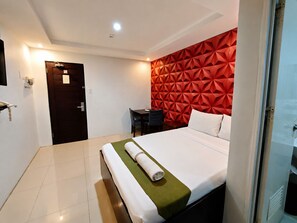 Une chambre dâhĂŽtel avec un lit, un bureau et un mur dĂ©corĂ© de motifs gĂ©omĂ©triques rouges.