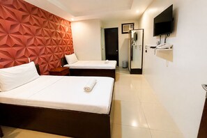 Une chambre d’hôtel avec deux lits, une télévision, un minibar et une porte donnant sur une salle de bain.