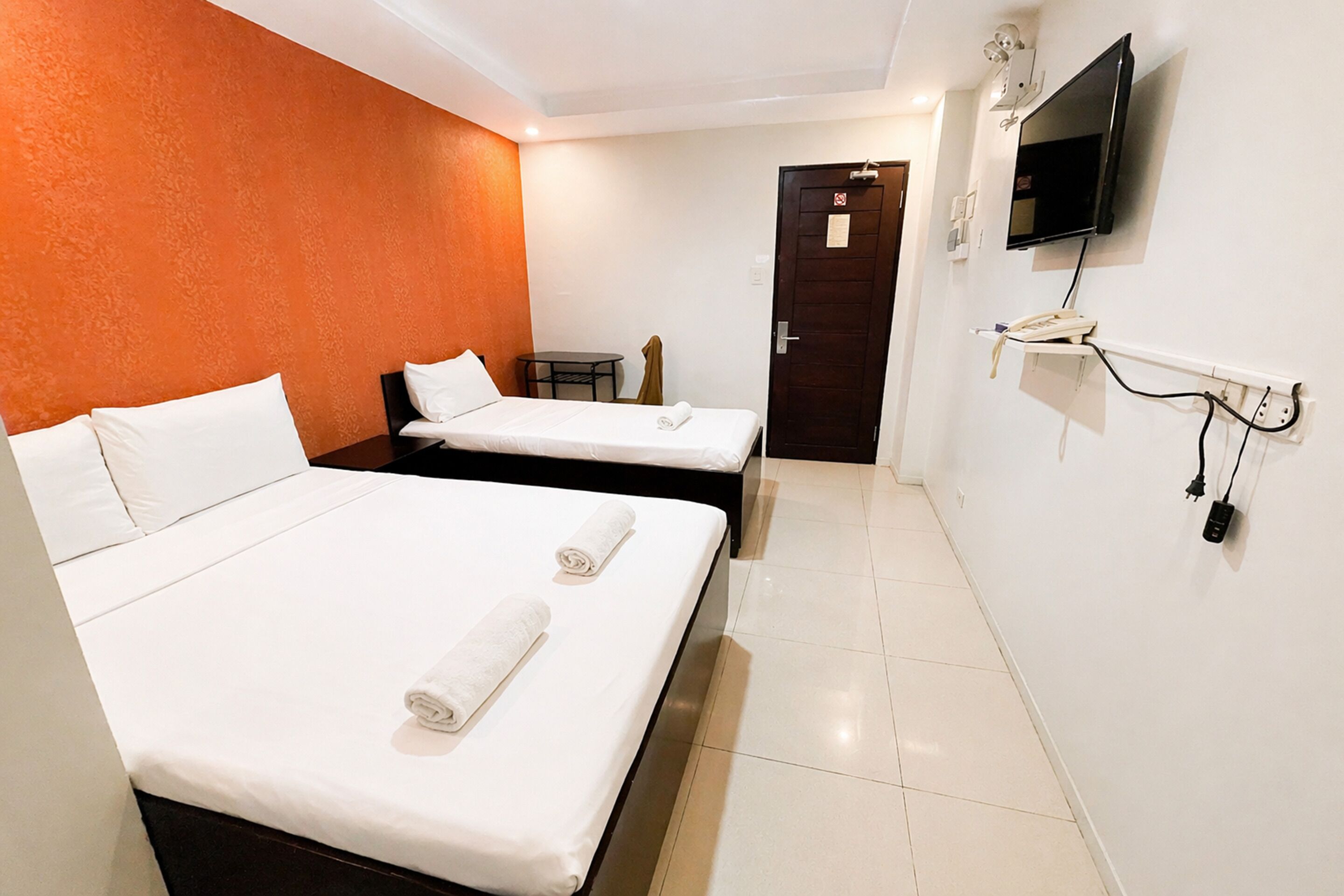 A hotel room with two beds, a TV, and a small table.