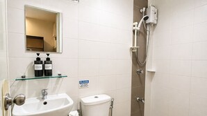 A bathroom with a sink, mirror, toilet, and shower. - Obrero Suites Davao (Davao)
