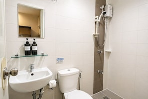 A bathroom with a sink, mirror, toilet, and shower.