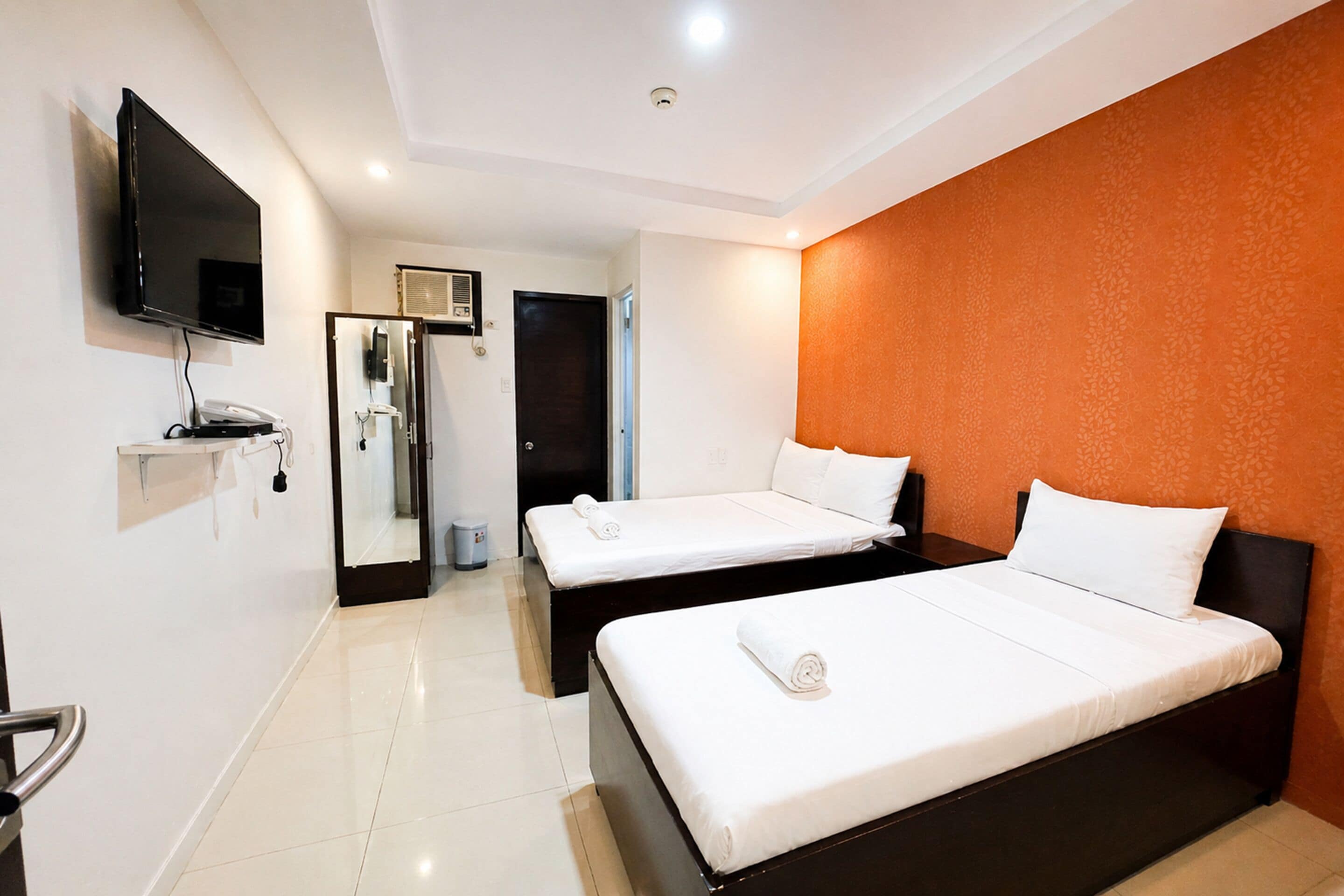 Une chambre d’hôtel avec deux lits, une télévision, un téléphone et un miroir.