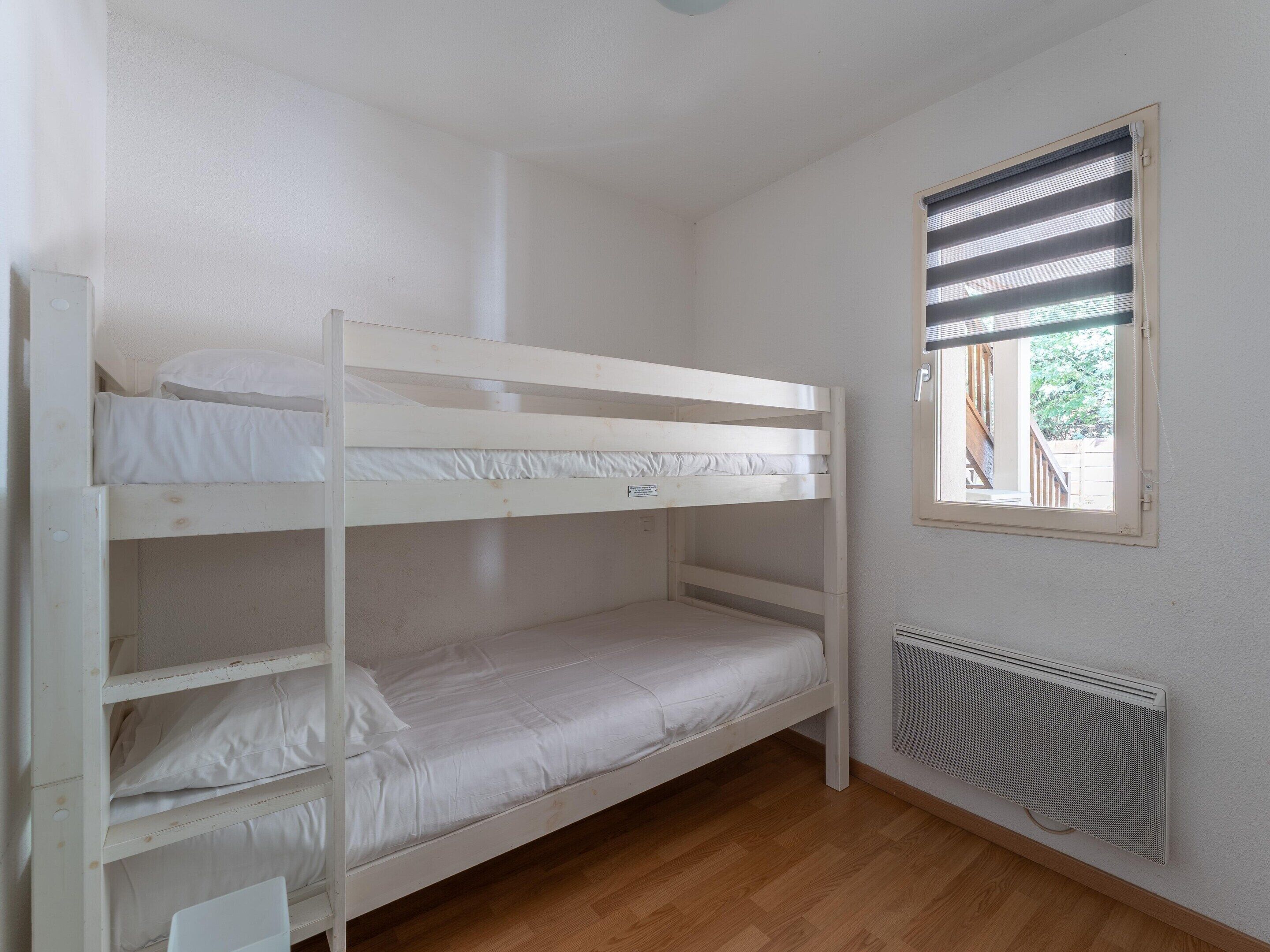 Habitación con literas, ventana y radiador.