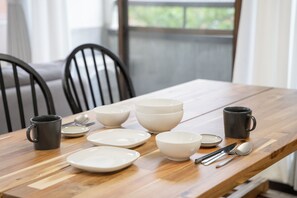 A dining table with bowls, plates, cutlery, and two mugs. - Panda Stay - Asakusa 5 mins Walk & Skytree Apt (Tokyo)