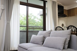 A modern living room with a sofa, curtains, a dining area, and a view through a large window. - Panda Stay - Asakusa 5 mins Walk & Skytree Apt (Tokyo)