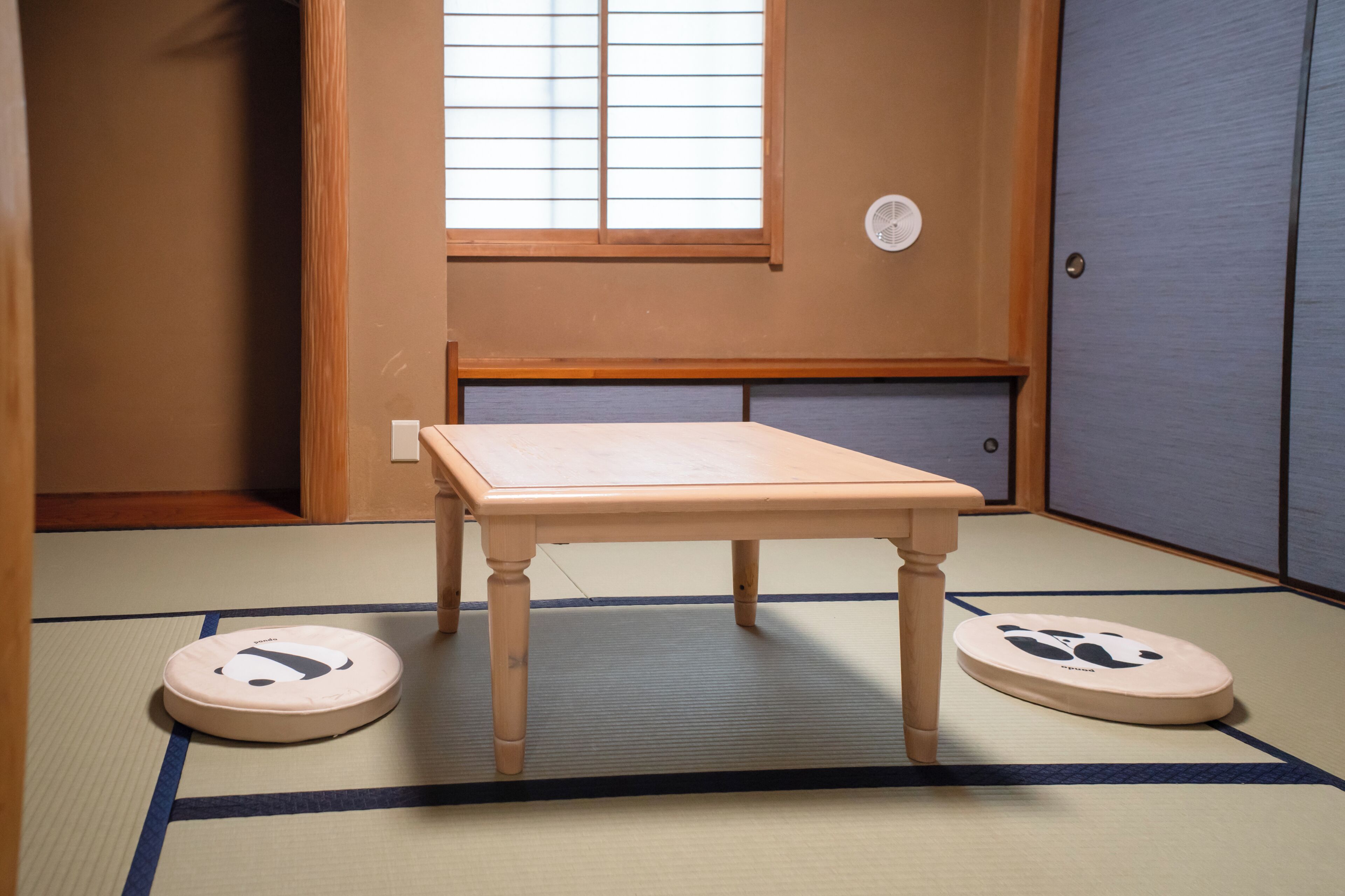 A tatami mat room with a wooden table and two tatami mats with panda designs.