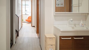 A hallway with a white sink, a mirror, and a wooden cabinet. - Panda Stay - Asakusa 5 mins Walk & Skytree Apt (Tokyo)