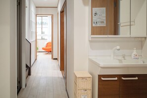 A hallway with a white sink, a mirror, and a wooden cabinet. - Panda Stay - Asakusa 5 mins Walk & Skytree Apt (Tokyo)
