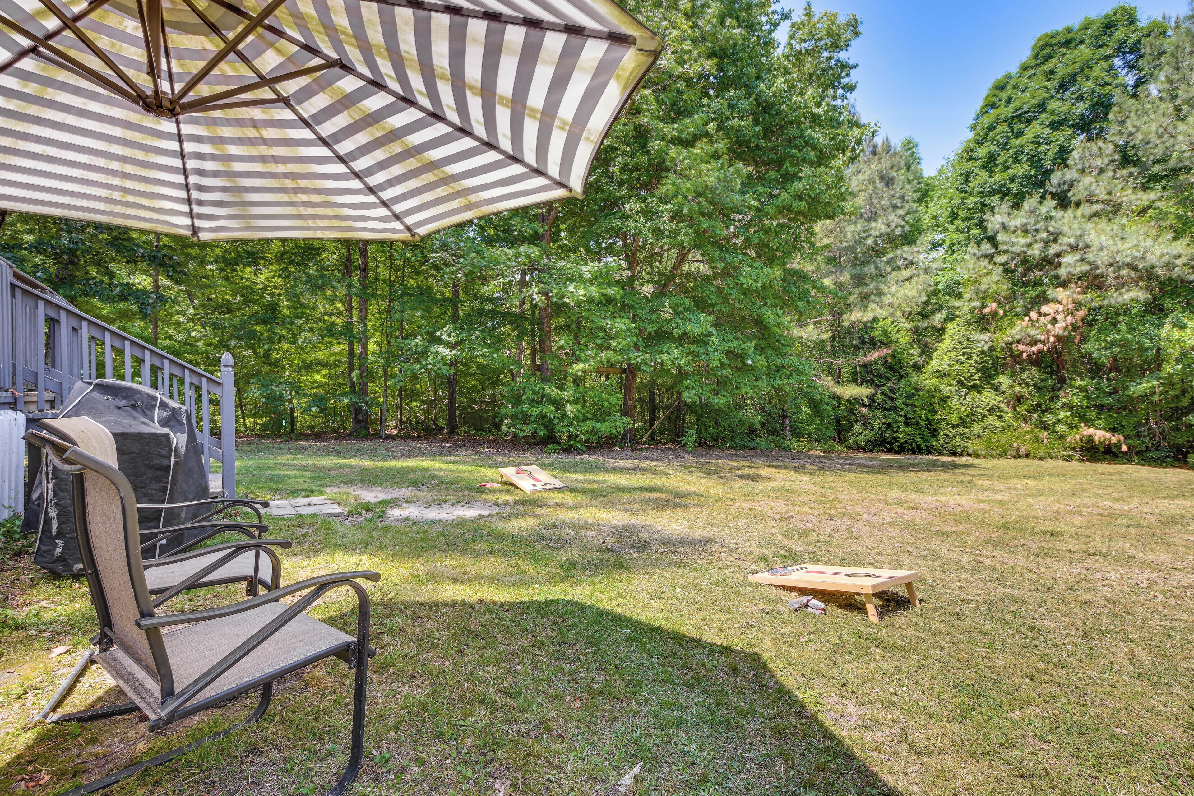 A backyard with a grill, a chair, and an umbrella.