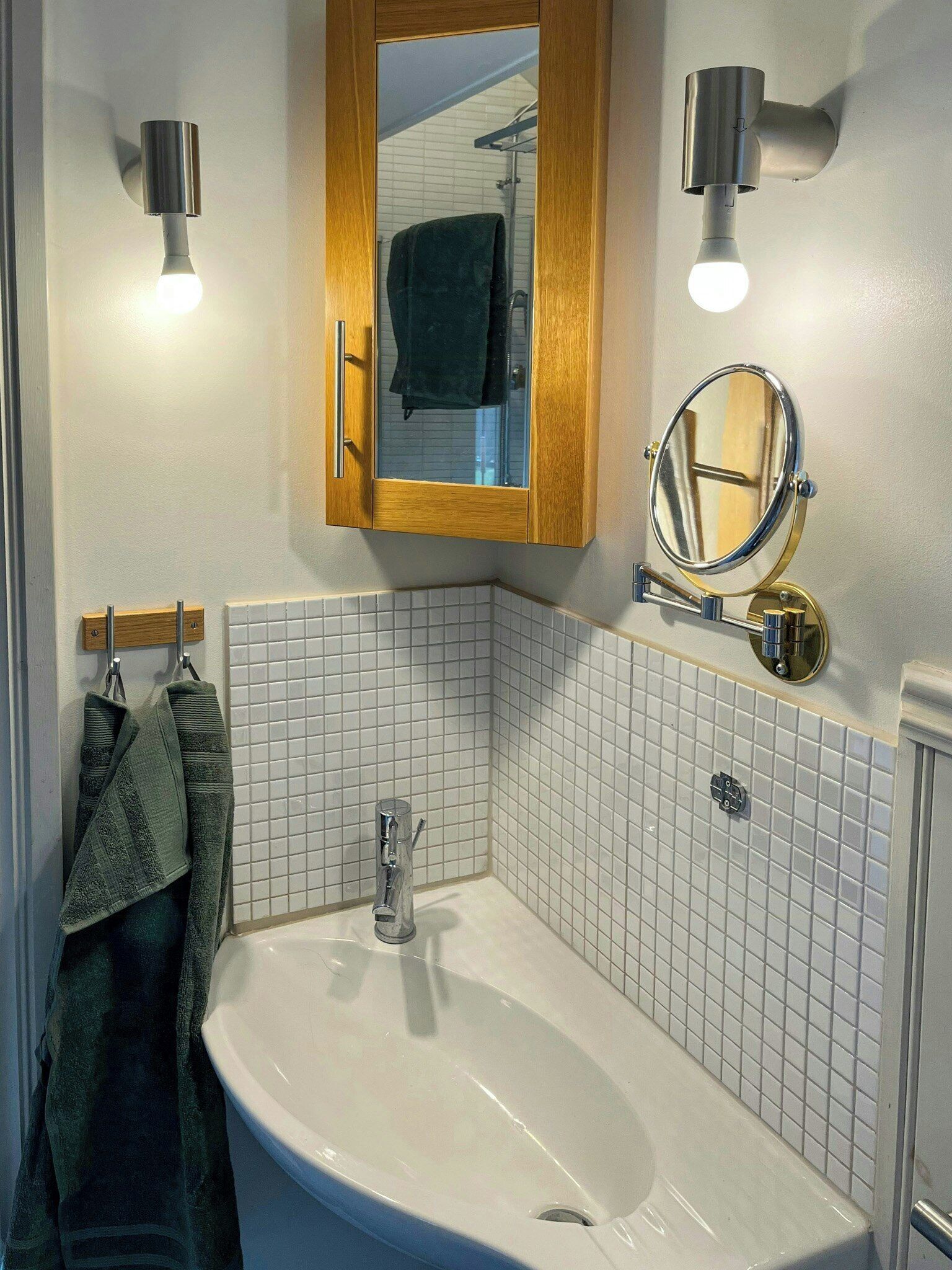 A bathroom with a white sink, a wooden cabinet with a mirror, and two wall-mounted lights.