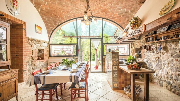 A rustic dining area with a brick ceiling, a large arched window, and a stone wall. - Villa with private pool among Siena's olive groves (Rapolano Terme)
