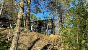 A cabin in a forest with a circular window and a door.