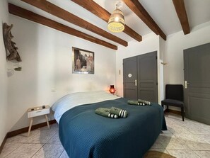 A bedroom with a bed, a nightstand, a chair, a wardrobe, and a hanging light fixture. - La Maison d'Artzamendi - Mountain view (LOUHOSSOA)