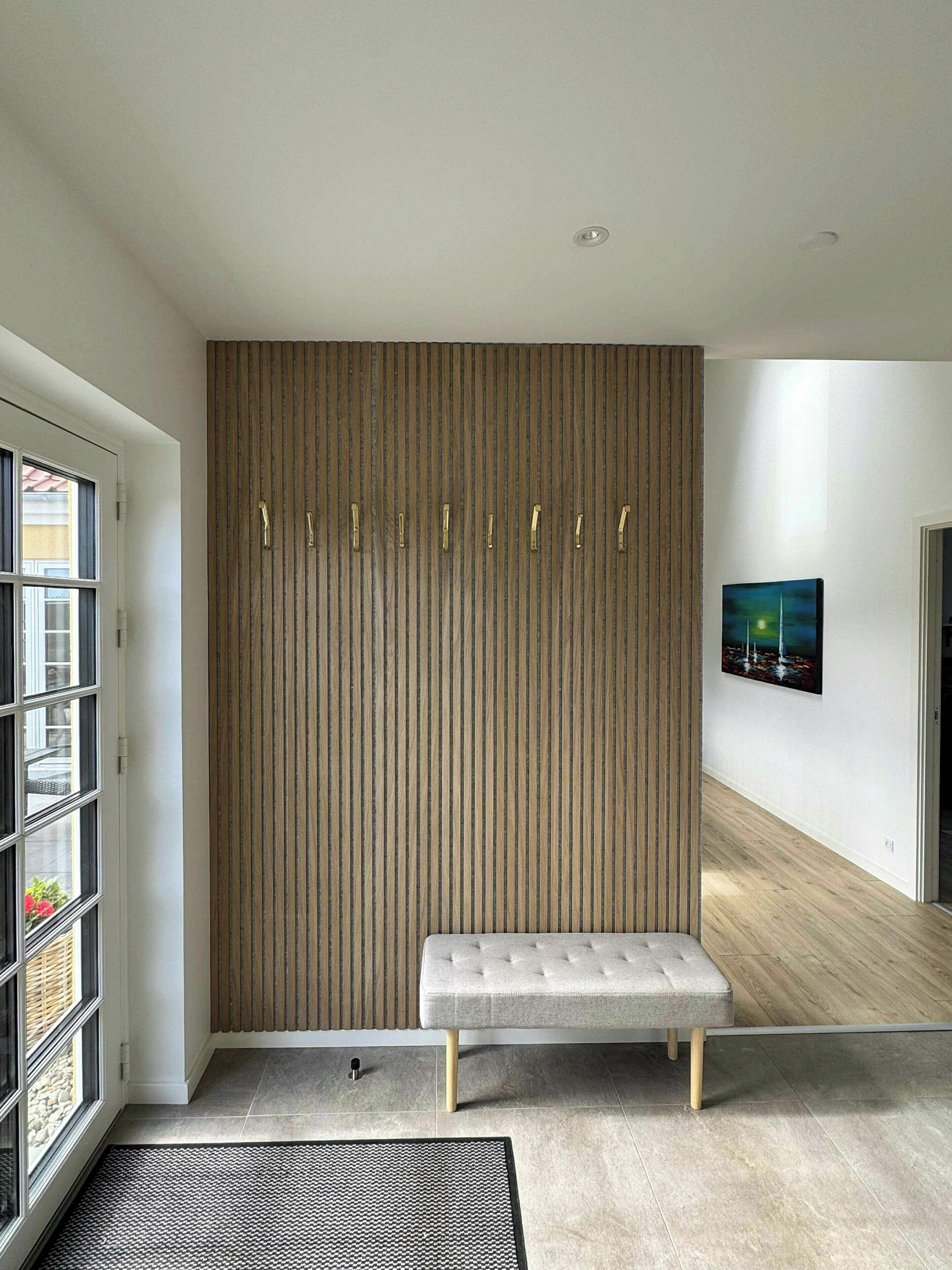 A modern interior with a bench, a wall with vertical lines, and a painting.