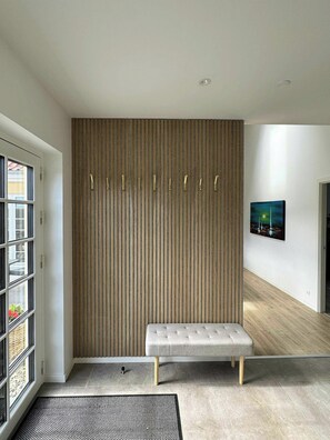 Un interior moderno con un banco, una pared con líneas verticales y un cuadro.