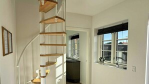 Un interior moderno con una escalera de caracol, una zona de cocina y un espacio comedor con vistas.