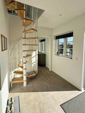 Un interior moderno con una escalera de caracol, una zona de cocina y un espacio comedor con vistas.