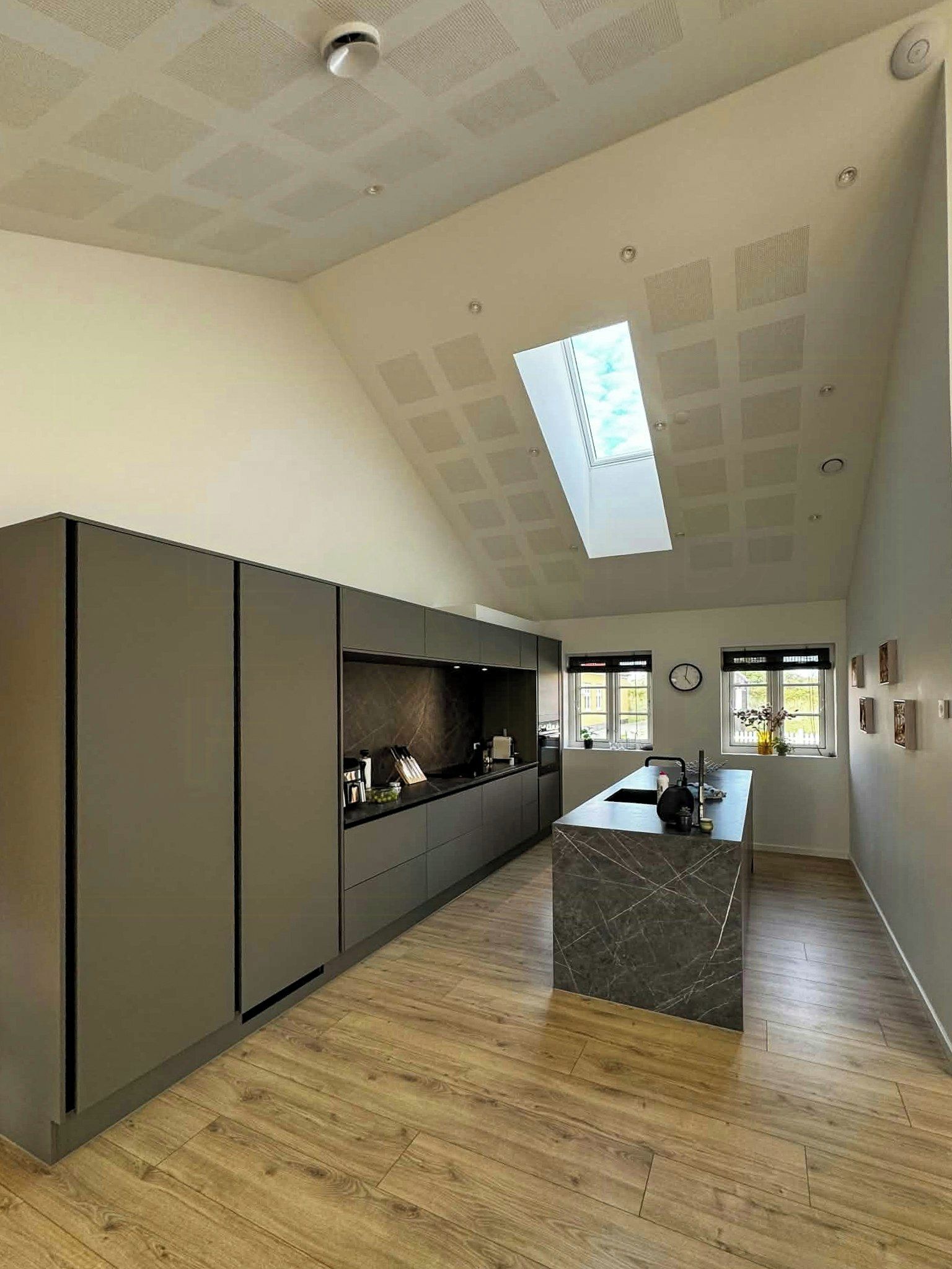 Una cocina moderna con una isla central, suelo de madera y tragaluz.