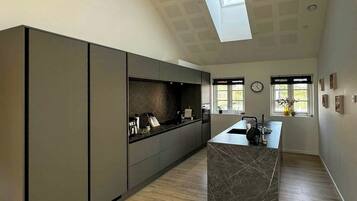 Una cocina moderna con una isla central, suelo de madera y tragaluz.