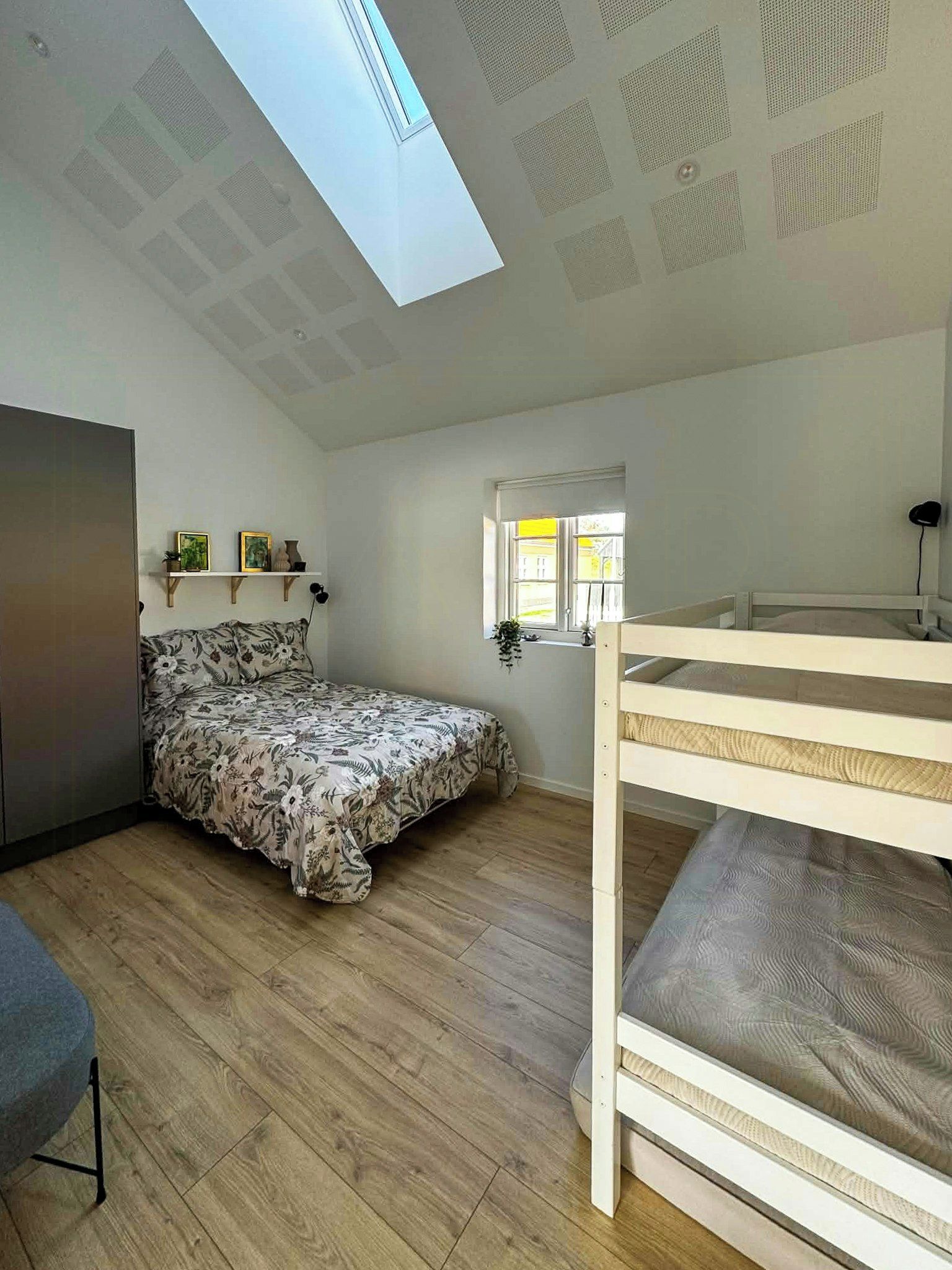 Une chambre avec un lit superposé, une grande fenêtre et un puits de lumière.