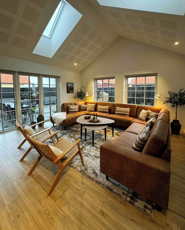 A spacious living room with a large sectional sofa, a wooden coffee table, and a skylight.