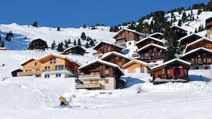 A cluster of wooden chalets on a snowy mountain slope with clear skies. - Spacious 8-guests Holiday Apartment (Les Angles)