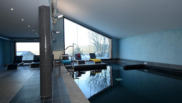 An indoor swimming pool with a view of mountains, lounge chairs, and a tiled floor. - Spacious 8-guests Holiday Apartment (Les Angles)