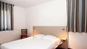 A hotel room with a bed, a chair, a nightstand, and a wall-mounted lamp. - Spacious 8-guests Holiday Apartment (Les Angles)