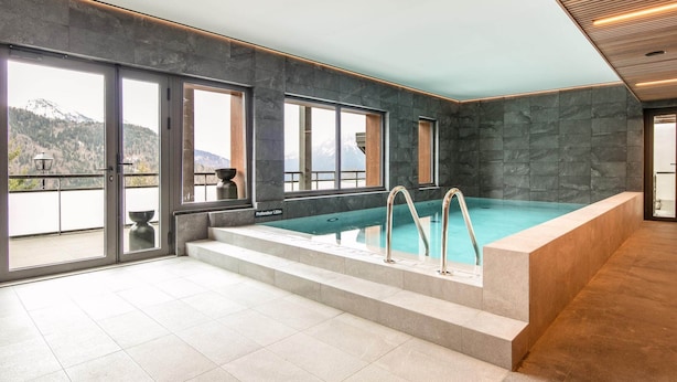 Una piscina coperta con vista sulle montagne, pareti in pietra e pavimento piastrellato.