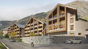 Un moderno hotel a più piani con balconi, un muro in pietra e vista su un paesaggio montuoso.