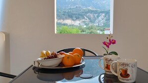 Ett matbord med en skål med frukt, två kaffemuggar och en orkidé i en kruka.