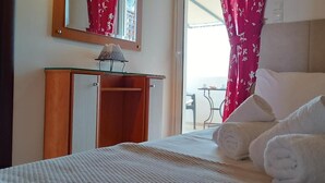 Quarto de hotel com cama, mesa de cabeceira com abajur, espelho e janela com cortinas.