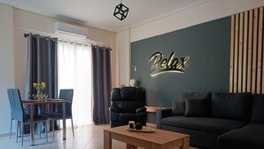 Uma sala de estar moderna com sofá, mesa de jantar com cadeiras, mesa de centro e um letreiro fixado na parede com a inscrição 'Relax'.