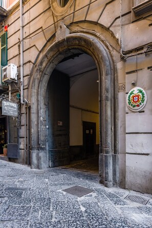 An arched doorway leading into a building with a plaque and a sign above it. - Maison Gennaro - Naples Heritage Stay (Naples)