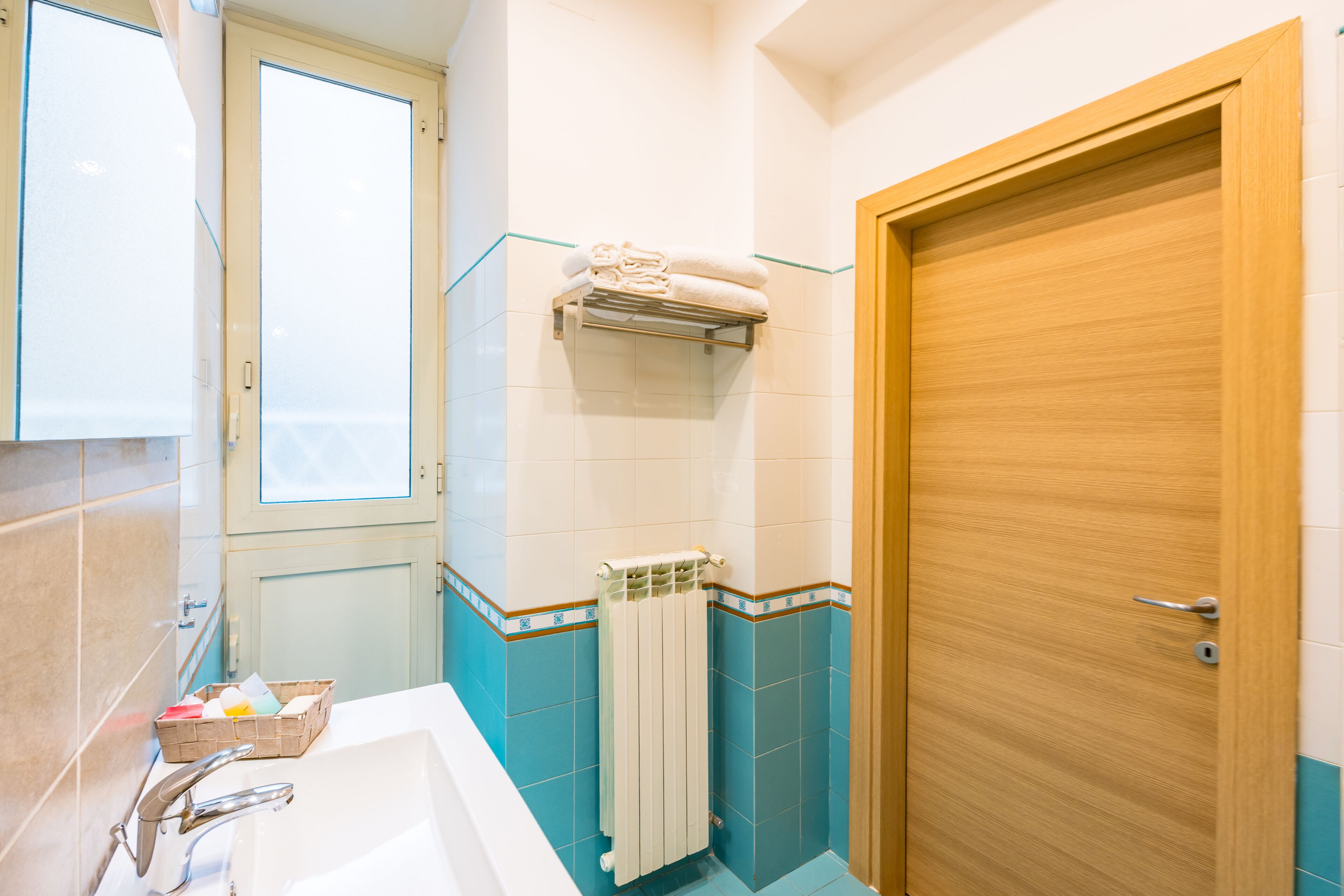 Ein Badezimmer mit einer Badewanne, einem Handtuchhalter, einer Holztür und einem Fenster.